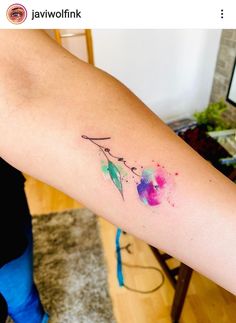 a woman's arm with a watercolor arrow tattoo on the left side of her arm