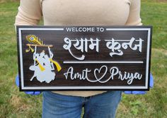 a person holding up a sign that says welcome to amit and priya on it