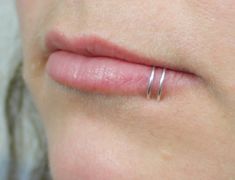 a woman's nose with two thin silver rings on her left side and the other end of her lip