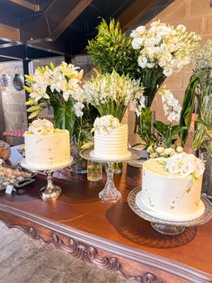 a table topped with three white cakes and flowers