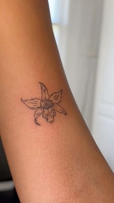 a woman's arm with a small flower tattoo on the left side of her arm