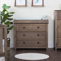 a baby crib and dresser in a room with two framed pictures on the wall