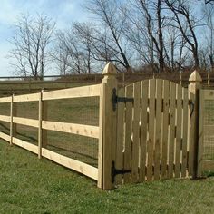 a wooden fence in the middle of a grassy field