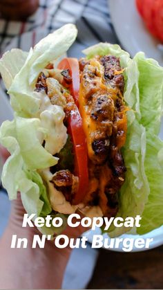 a hand holding a lettuce and tomato sandwich with the words keto copycat in n'out burger