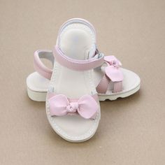 The Leigh sandal features a knotted bow, a lovely touch that is hard to miss. This sandal will easily amplify her charm and confidence wherever she goes. Lightly padded footbed with memory foam Leather upper and lining Lightly padded collar Hook and loop velcro ankle strap Light EVA wedge outsole Toddler sizes 5-13; Youth sizes 1-2. Size Chart (in-sock length, measured from inside): Size 5 6 7 8 9 10 In. 5.25 5.6 5.85 6.25 6.5 6.8 Size 11 12 13 1 2 In. 7.1 7.4 7.8 8.1 8.4 Pink Ankle Strap Sandals With Bow, Pink Bow Sandals With Synthetic Material, Slip-on Synthetic Sandals With Bow Detail, Girls Sandals Kids, Toddler Sandals Girl, Bow Sandals, Toddler Sizes, Memory Foam, Ankle Strap