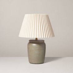 a table lamp with a white shade on it's base and a light bulb in the middle