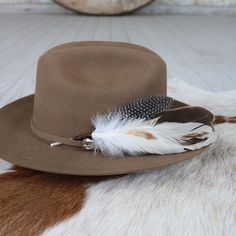 The Cheyenne hat feather is hand constructed with brown and cream feathers for a natural hat accent. Tuck into the band of any hat.Made with a mix of turkey, guinea, and rooster feathers.Approximately 8 inches long, sizes may vary due to being made with natural materials. Natural Feathers Approx. 8 inches - sizes may vary slightly Tuck into the band of any hat! *Hat not included* CA Residents: Prop 65 Warning ↗️ Brown Hat Bands With Feathers For Western-themed Events, Brown Top Hat For Country Events With Short Brim, Brown Top Hat With Short Brim For Country Events, Brown Short Brim Top Hat For Country Events, Brown Top Hat For Kentucky Derby And Country Events, Brown Flat Brim Top Hat For Country Events, Brown Wide Brim Top Hat For Country Events, Curved Brim Hat Bands With Feathers For Western-themed Events, Rustic Brown Brimmed Top Hat