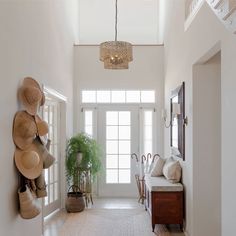 an entry way with white walls and wooden furniture, potted plants on the wall