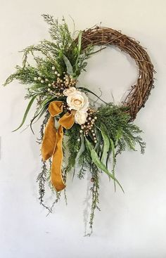 a wreath with flowers and greenery hanging on the wall