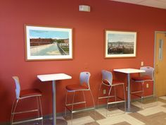 three tables and two chairs in a room with red walls, white tile flooring and pictures on the wall