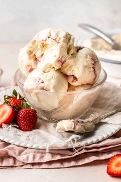 a bowl filled with ice cream and strawberries on top of a cloth covered plate