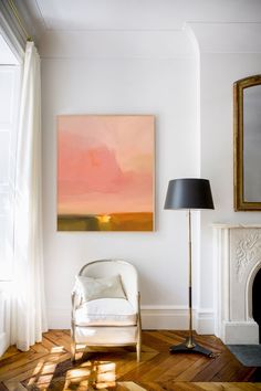 a living room with a painting on the wall and a chair in front of it