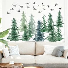 a living room with trees painted on the wall and birds flying over it in the air