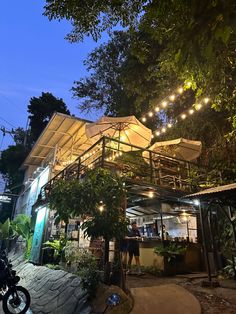 an outdoor restaurant with lots of lights on the roof and people standing outside at night