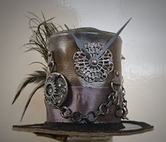 IMPORTANT NEWS!!  Due to the UK leaving the EU, postage prices have increased but have kept them as low as I can for my customers. If you would like to purchase more than one item, please contact me first so I can invoice you with the lowest postage price. Unique, leather mini top hat. Steampunk style. Attaches to the head by 2 alligator clips Approx Size: Brim Width 15.5cm                         Height 10cm Bespoke mini top hats available. One of a kind Details: Leather top hat Metal details Metal buckle Ribbon band Clock parts Metal chain Black feathers Peacock feather Metal spike Tracked and signed postage worldwide available, please contact me before purchasing. Vintage Top Hat With High Crown For Cosplay, Steampunk High Crown Mini Hat For Themed Events, Vintage High Crown Top Hat For Cosplay, Steampunk Mini Hats For Halloween, Steampunk Brimmed Mini Hats For Cosplay, Handmade Vintage High Crown Top Hat, Steampunk Top Hat With High Crown For Themed Events, Steampunk Costume Mini Hat With Short Brim, Steampunk Mini Hats For Festivals