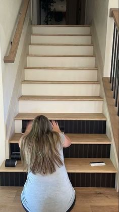 a woman sitting on the floor in front of some stairs