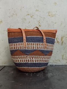 Handwoven in the Eastern Kenya by the akamba kenya, this bag is made out of sisal fiber and finished off using leather that is a by product of the meat industry in kenya.  Dimensions  Base diameter 8 inches Height 11 inches Top 14 inches Leather Bucket Straw Bag For Market, Natural Leather Handwoven Crochet Bag, Handwoven Leather Tote Crochet Bag, Handwoven Leather Crochet Tote Bag, Brown Handwoven Tote Straw Bag, Brown Handwoven Straw Tote Bag, Brown Jute Straw Bag For Market, Handwoven Leather Basket Shoulder Bag, Traditional Brown Bag With Woven Leather