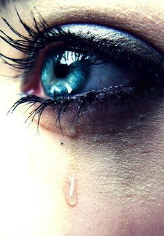 a woman's blue eye with water drops on her lashes and the bottom part of her eyelashes