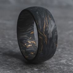 The Grand Prix is a forged black carbon fiber wedding ring crafted with formula-one grade 24,000 carbon fiber tow - pressurized with gold leaf flake, giving it a signature "marbled" aesthetic. Each carbon fiber ring is going to have a unique pattern, so every ring will be truly one-of-a-kind. If you're looking for a wedding ring that's exclusive to you, The Grand Prix is the carbon fiber ring to go with. This ring is made exclusively with carbon fiber, which means it's safe for wear by electrici Mens Tungsten Wedding Rings, Rustic Mens Wedding Bands, Carbon Fiber Ring, Unique Mens Jewelry, Titanium Mens Wedding Band, Mens Wedding Rings Gold Unique, Unique Men’s Wedding Rings, Couple Wedding Rings Unique