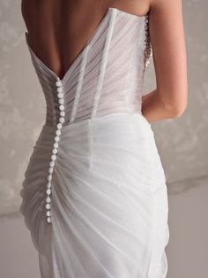 the back of a woman's wedding dress, with pearls on the straps and shoulders