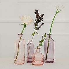 three vases with flowers in them sitting on a table