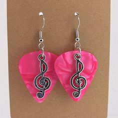 a pair of pink heart shaped earrings with musical notes on it's earwires