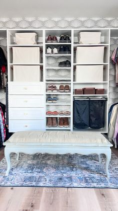 a white bench sitting in front of a closet filled with clothes and shoes on shelves