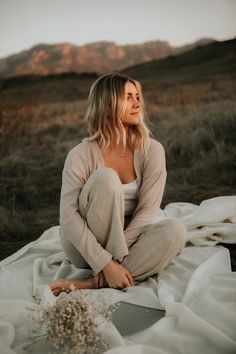 a woman sitting on top of a blanket in the desert