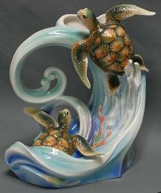 a ceramic figurine depicting two sea turtles riding a wave