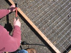 a person is working on some kind of metal wire fence that's attached to the ground