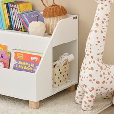 a giraffe stuffed animal next to a book shelf with books on it's sides