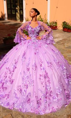 Look regal and radiant in this lilac purple ball gown quinceañera dress. The beautiful pastel hue perfectly complements the 3-D flowers that pop against the embroidered lace corset bodice and poofy glitter tulle skirt. For an extra princess vibe, this purple quince dress has a sheer bolero jacket with matching embellishments and dainty bell sleeves. Step into your milestone celebration in style when you wear this lilac purple quinceañera dress. Purple Quince Dress, Color Lila Pastel, Princess Vibe, Purple Ball Gown, Quince Stuff, Purple Quinceanera Dresses, Purple Quince, Quince Dress, Flower Embellishments