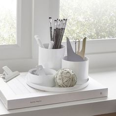 a white desk with pens, pencils and other office supplies on top of it