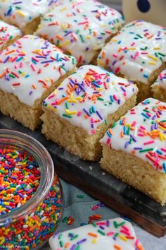 several pieces of cake with white frosting and sprinkles on a tray