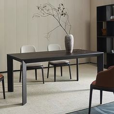 a dining room table with chairs and a vase on the table in front of it