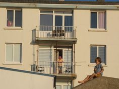 two people are sitting on the balcony of an apartment building