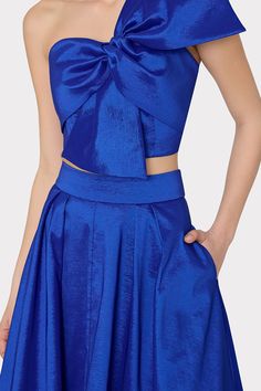 Cut from a bright blue, luxurious and crisp taffeta fabric, this voluminously full skirt falls to a modest, midi length. It has two side pockets and a zipper in the back to close. For the full look, pair it with its coordinated Laney Bow Crop Top. Elegant Blue Skirt For Prom, Blue Evening Dress With Lined Skirt, Blue Lined Skirt Evening Dress, Party Satin Skirt With Folds, Blue Voluminous Skirt For Parties, Voluminous Blue Skirt For Party, Blue Flared Evening Dress, Blue Flared Skirt Evening Dress, Blue Party Dress With Flared Skirt