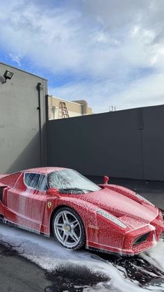 a red sports car is parked on the street in front of a building with snow all over it