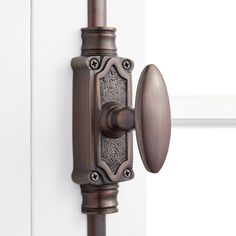 an old fashioned door handle on the side of a white door with a brown curtain rod