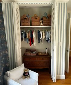 an open closet with clothes hanging on the wall and a teddy bear sitting on a chair