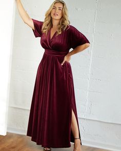 a woman in a long dress posing for the camera with her hand on her hip