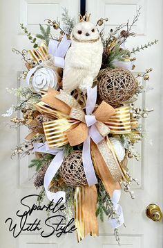 an owl is sitting on top of a wreath that has been decorated with gold and white ribbons