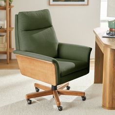 a green office chair sitting on top of a white rug next to a wooden table