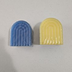 two soap bars sitting next to each other on a white counter top, one blue and one yellow