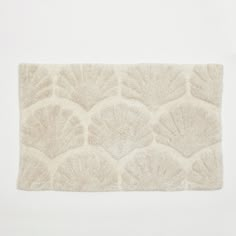 a white rug with an intricate design on the front and back side, against a white background