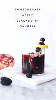 a glass filled with blackberry sangria sitting on top of a white plate