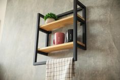 two wooden shelves holding vases and other items on a gray wall with a checkered towel hanging from it