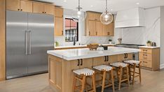 a kitchen with wooden cabinets and white marble counter tops, an island with four stools