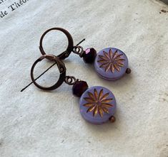 Purple Daisy Earrings.  These nature - inspired boho style earrings feature a faceted deep purple crystal on top of a lavender Czech glass circle with a gold stamped daisy. The beads are brass wire wrapped and hang 1.5 inches from handmade brass leverbacks. Simple and perfect for fall!  All my handmade earrings come in their own organza gift bag. To see my other nature - inspired jewelry-- http://www.etsy.com/shop/FuchsiaBloomStudio/search?search_query=nature To see my other woodland jewelry-- h Geometric Jewelry Design, Styled Jewelry, Glass Circle, Woodland Jewelry, Purple Daisy, Boho Style Earrings, Fall Earrings, Daisy Earrings, Purple Crystal