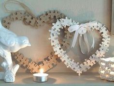 a candle and some puzzle pieces are on a shelf next to a heart shaped frame